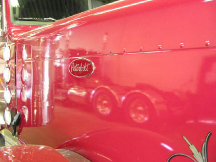 Peterbilt hood logo with truck wheels in reflection